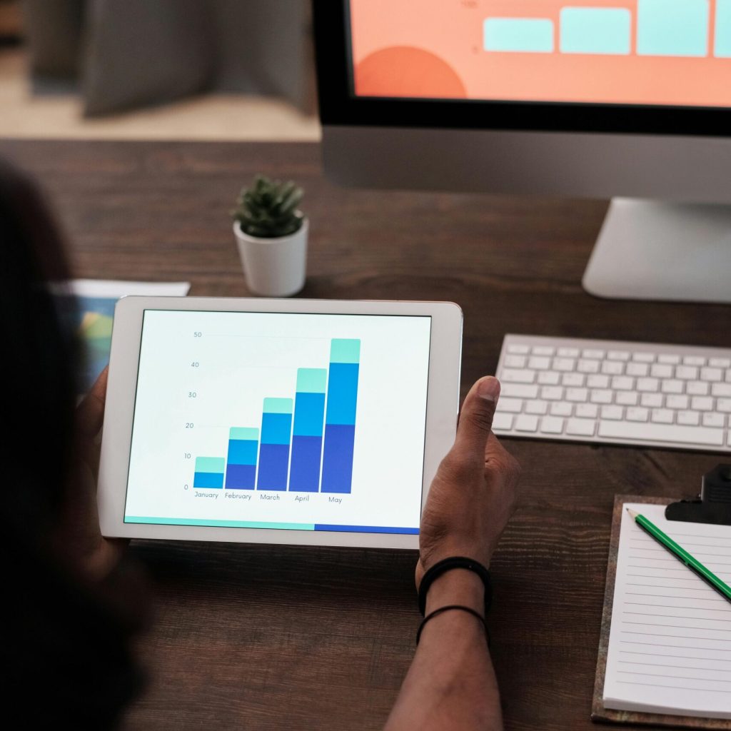 A person reviews statistical graphs on a tablet, showcasing data analysis and technology.