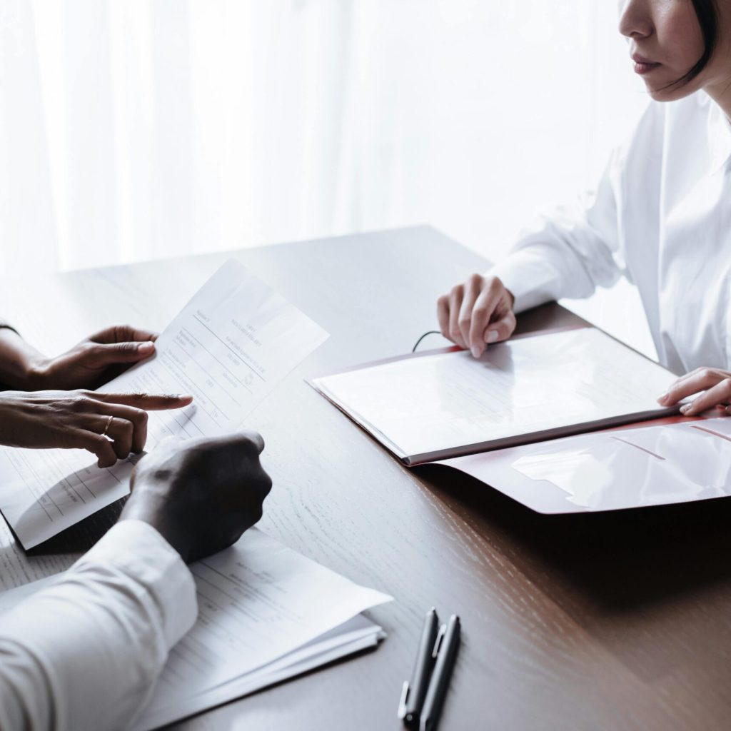 A diverse group of adults reviewing documents during a meeting at an office table.